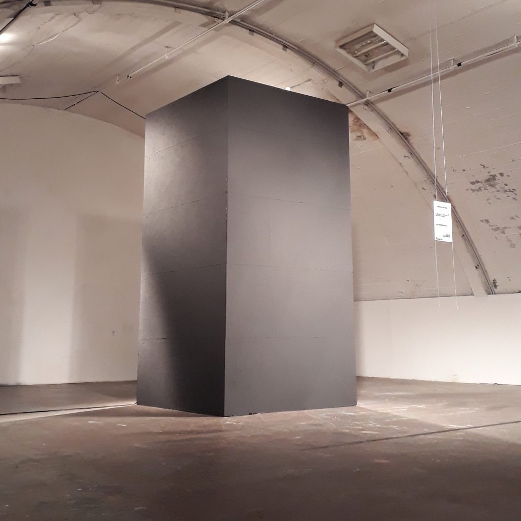 Foto einer weissen Halle mit einem grossen grauen rechteckigen Objekt.